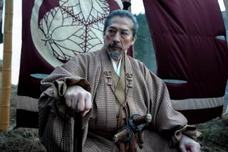 Hiroyuki Sanada as Yoshii Toranaga sitting with his fist out in front of a flag bearing a family crest