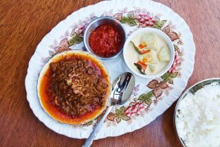 An overhead photo of a bowl of beef rendang with crispy shallots on a porcelain platter with chili at Cobi's in Santa Monica