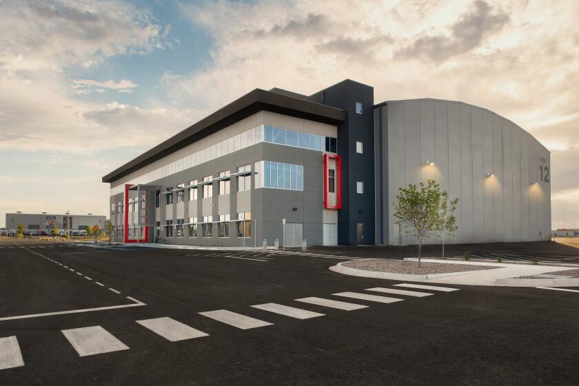 A gray soundstage on a freshly paved road under a partly cloudy sky.