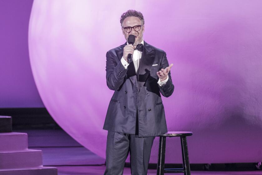 Man in suit standing on stage with a mic