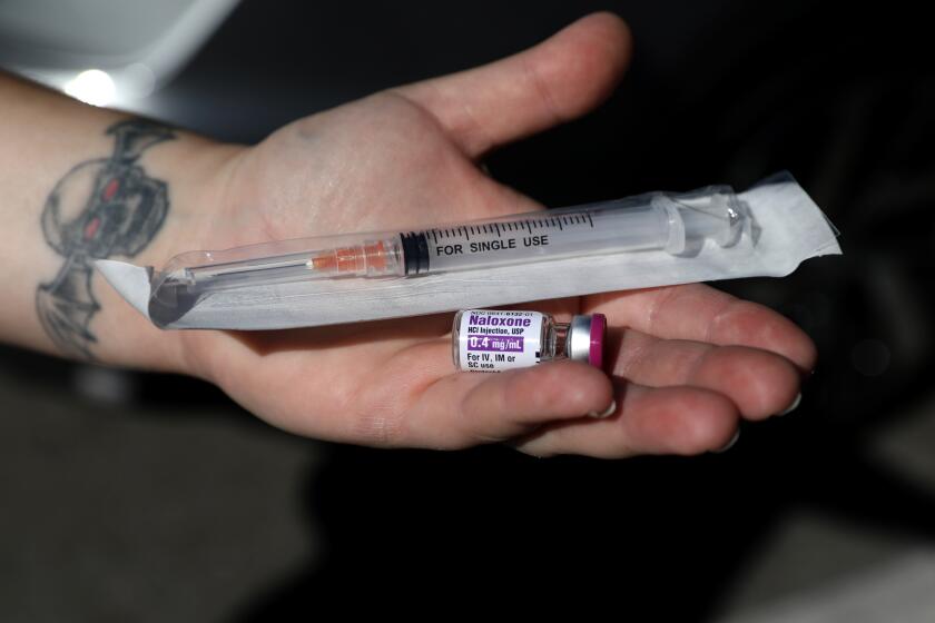 SANTA ANA, CA - FEBRUARY 10: Emily Pomerantz (cq), peer suuport case manager, of Harm Reduction Institute, shows a single dose of naloxone and a syringe used for naloxone kits to hand out to clients who use opioids on Thursday, Feb. 10, 2022 in Santa Ana, CA. Workers at the Harm Reduction Institute, which shut down its offices in Santa Ana after the city revoked its occupancy permit, hand out naloxone - a medicine that can reverse an opioid overdose - on the streets. The workers now have to operate out of a storage facility. (Gary Coronado / Los Angeles Times)